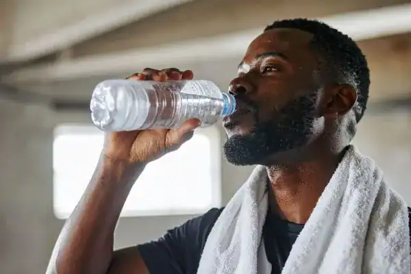 Hydration: The Secret Ingredient for a Toned Stomach and Enhanced Fitness 1 Image of man drinking water to improve hydration Rochester after work out.